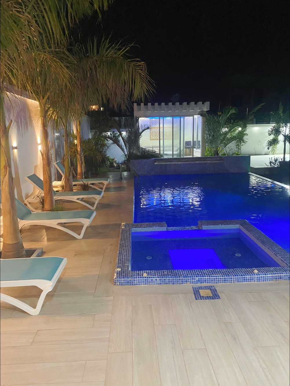 Vue nocturne de la piscine chauffée et des chaises longues