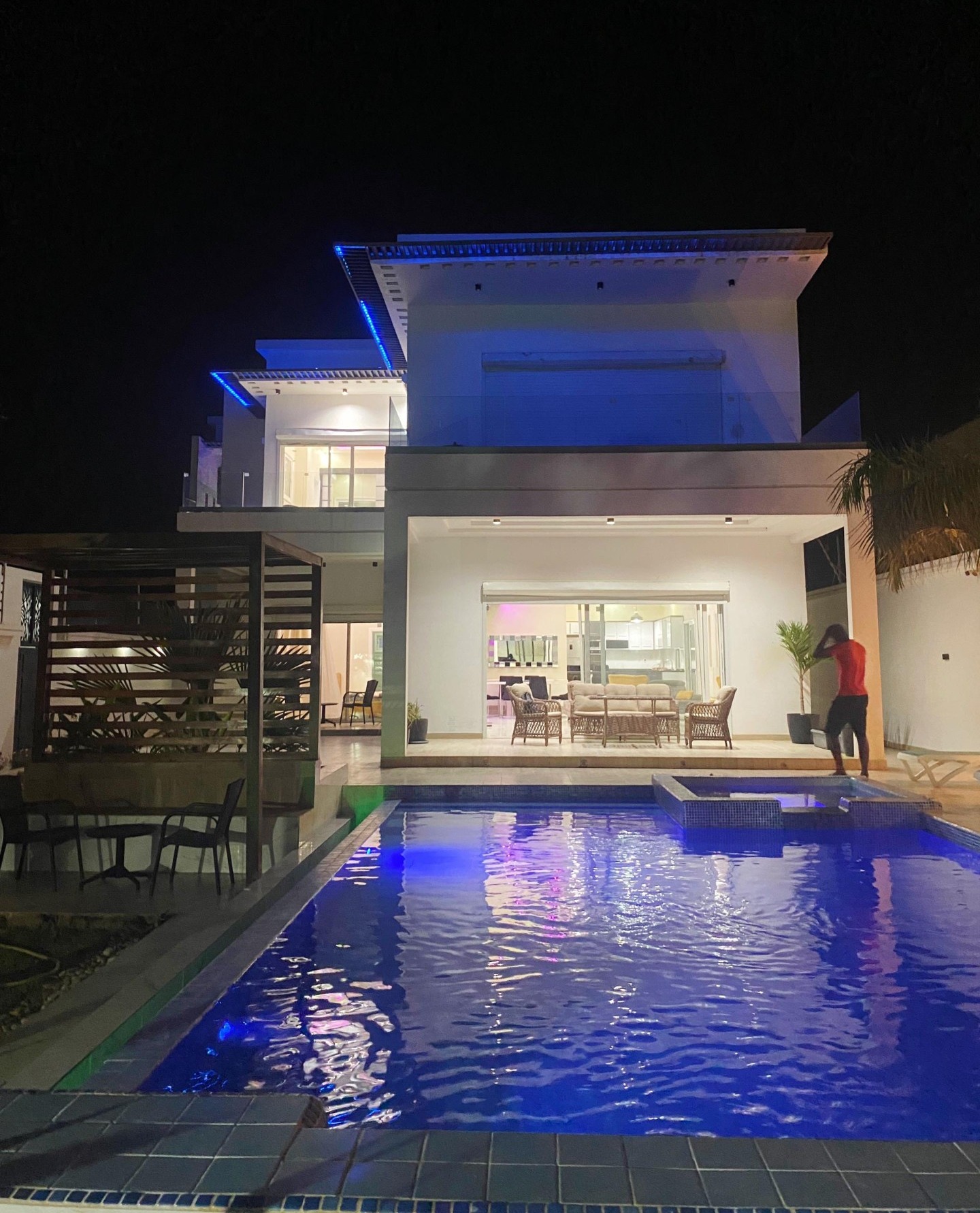 Façade de la villa illuminée de nuit avec piscine bleue